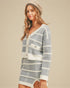 Woman wearing a gray and white striped sweater dress with a beige background