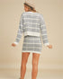 Woman wearing a gray and white checkered outfit on a beige background