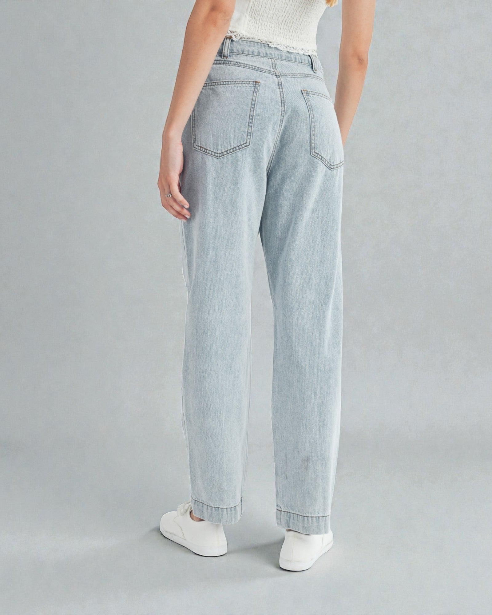 Light blue jeans worn by a person on a gray background