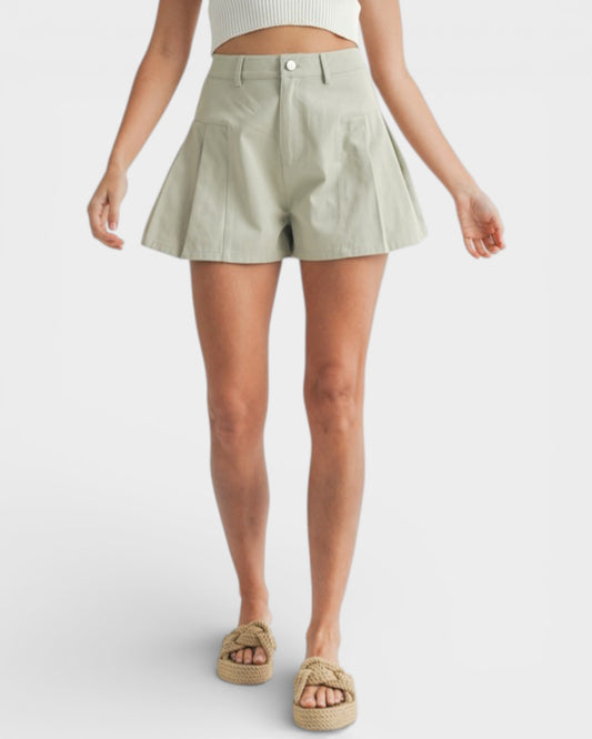 Person wearing a light green pleated skirt on a white background