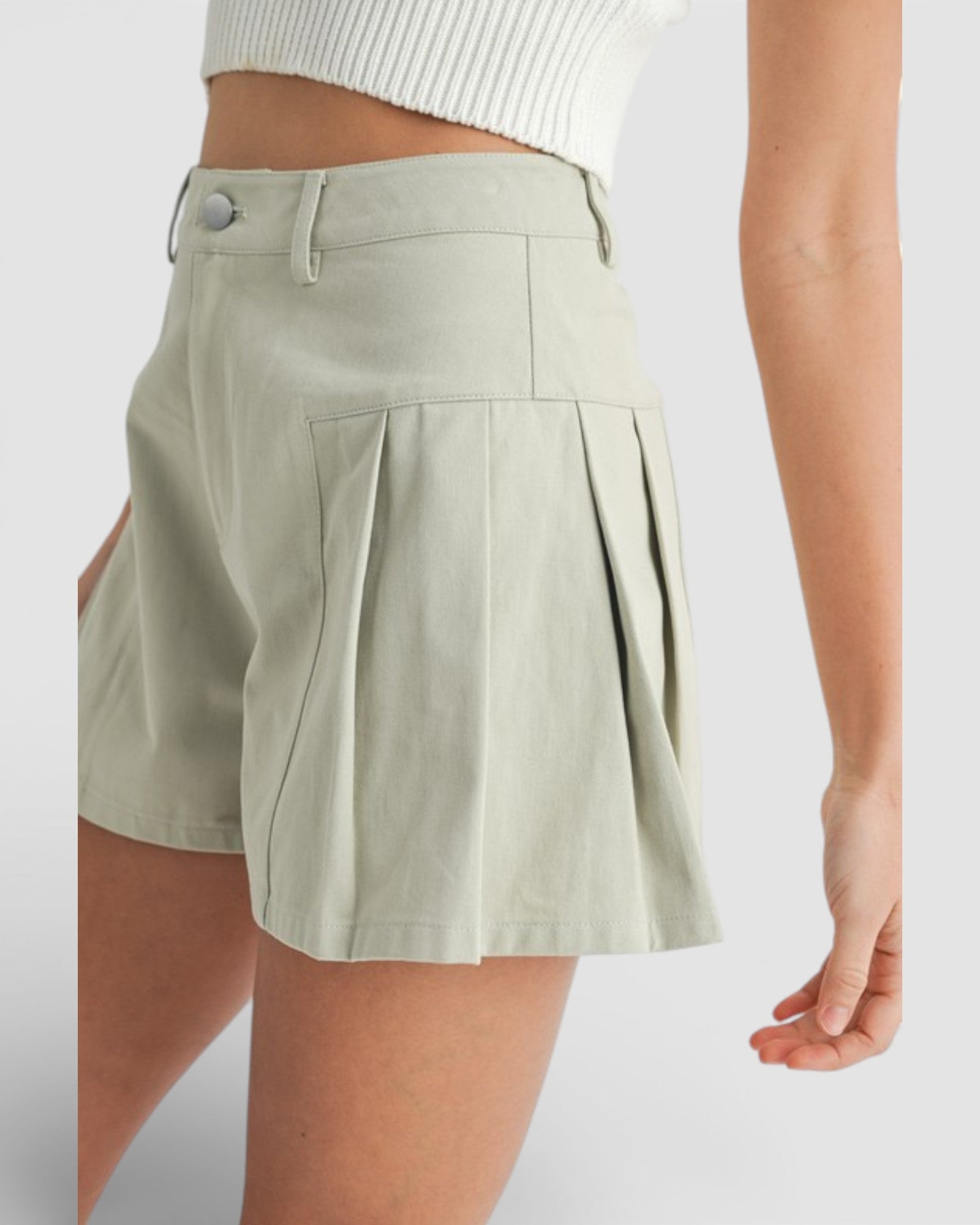Light green pleated skirt worn by a person on a white background