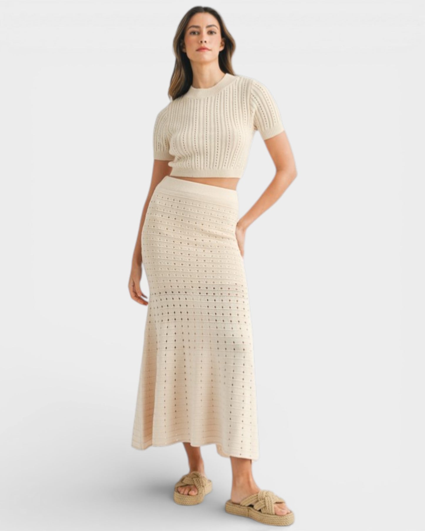 Woman wearing a beige knit top and skirt set on a white background