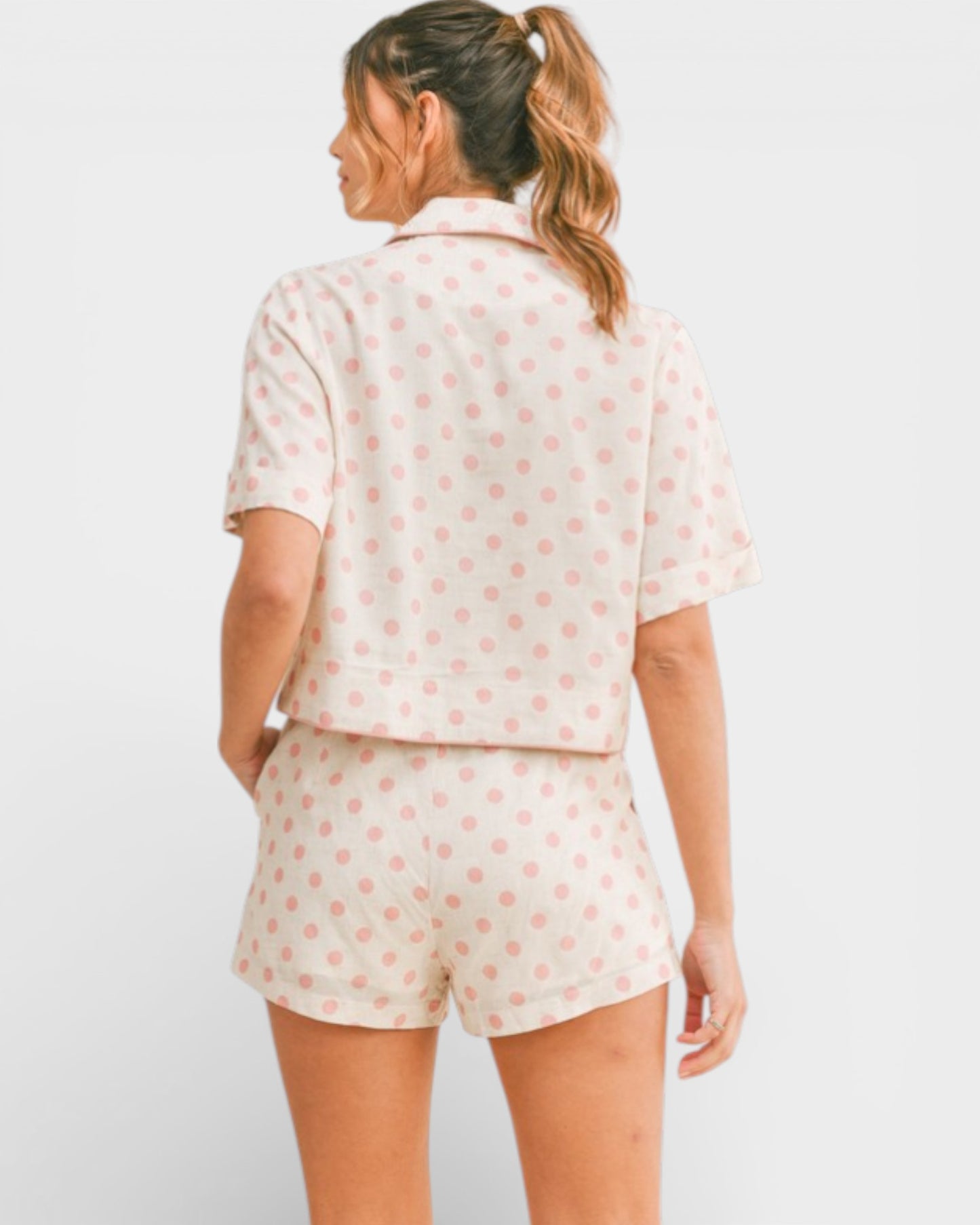 Woman wearing a polka dot pajama set on a white background