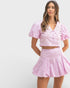 Woman wearing a pink outfit with a top and skirt on a white background