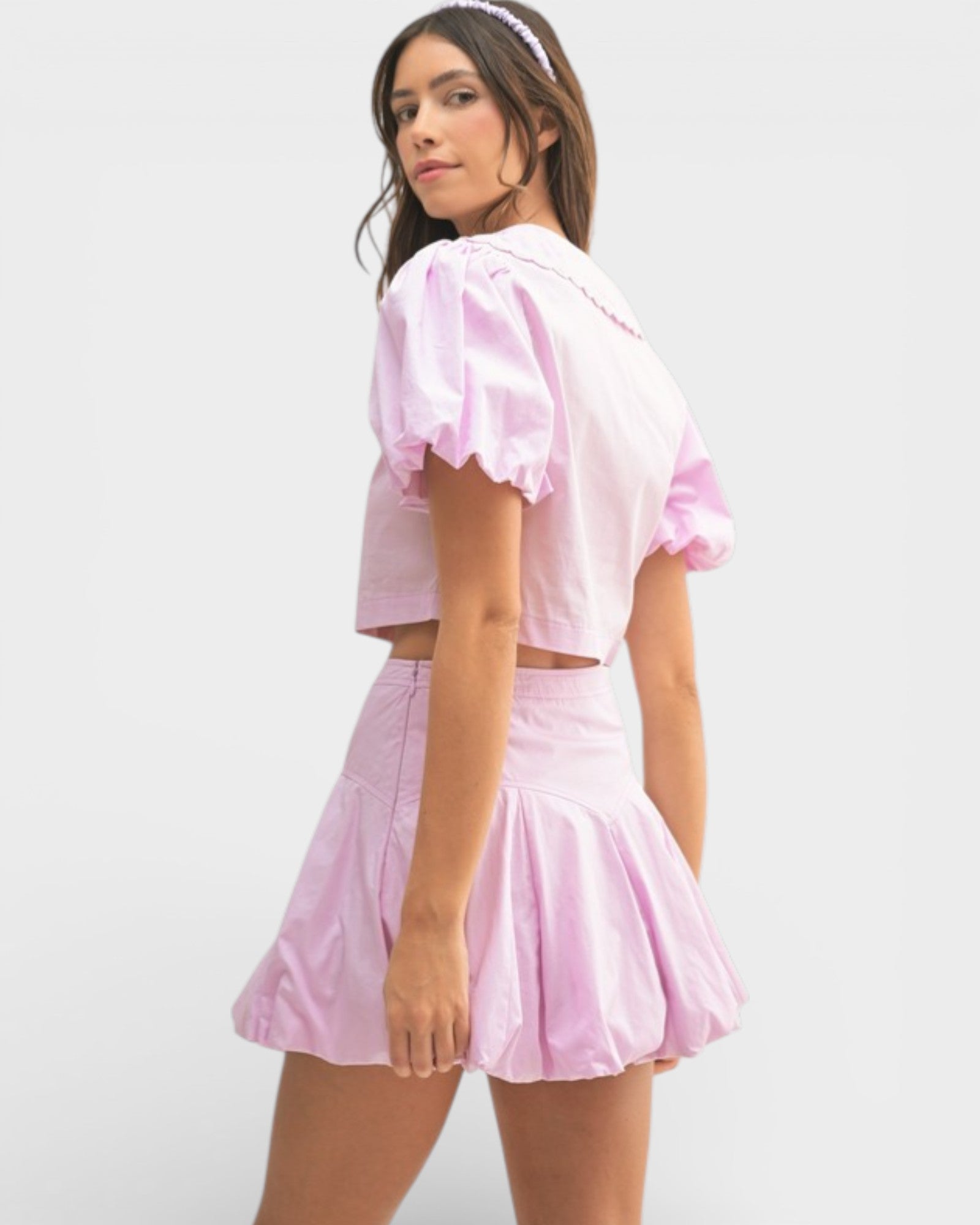 Woman wearing a pink outfit with ruffled sleeves on a white background