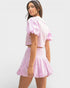 Woman wearing a pink outfit with ruffled sleeves on a white background