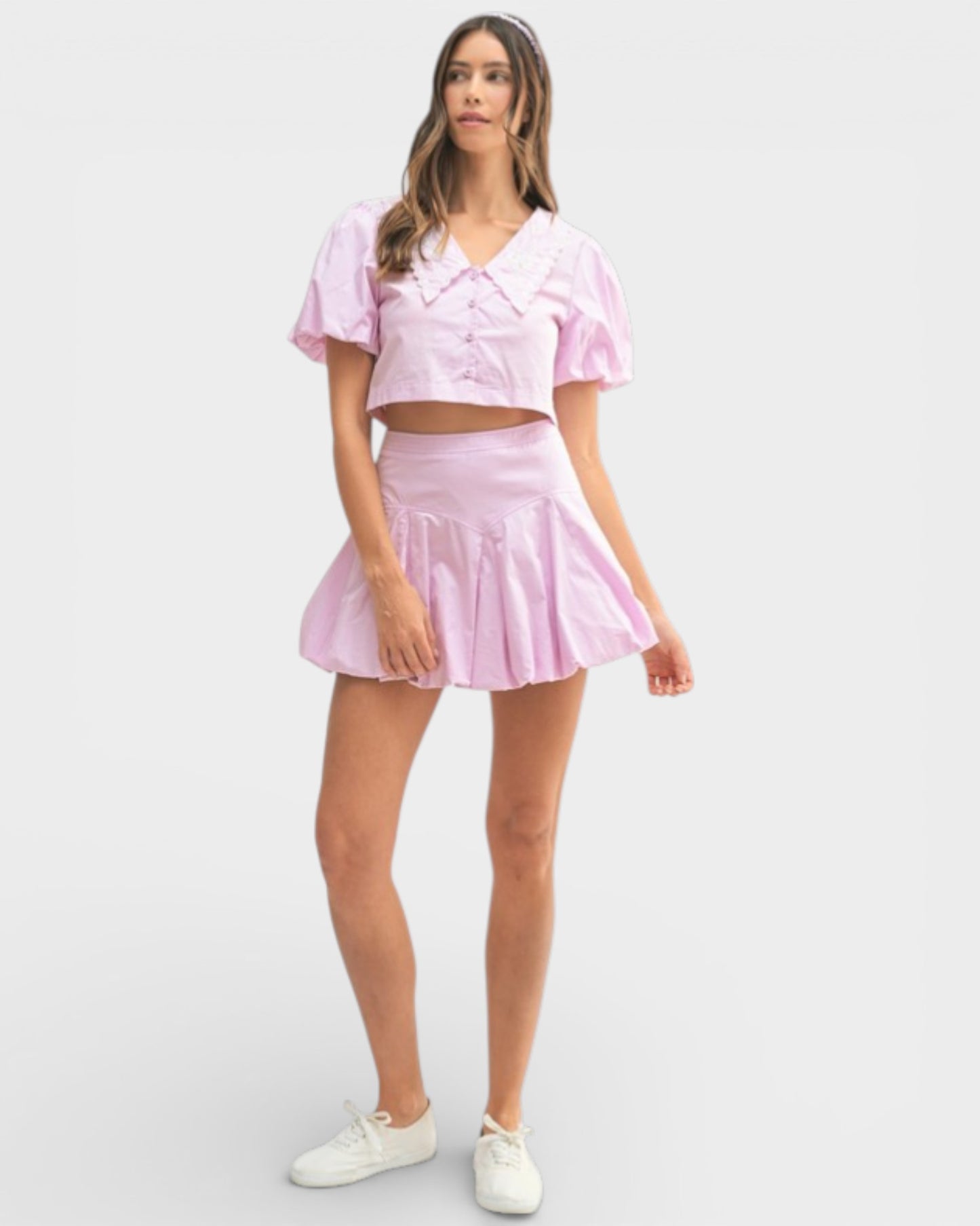 Woman wearing a pink outfit with a top and skirt on a white background