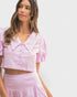 Woman wearing a pink outfit with ruffled details on a light gray background