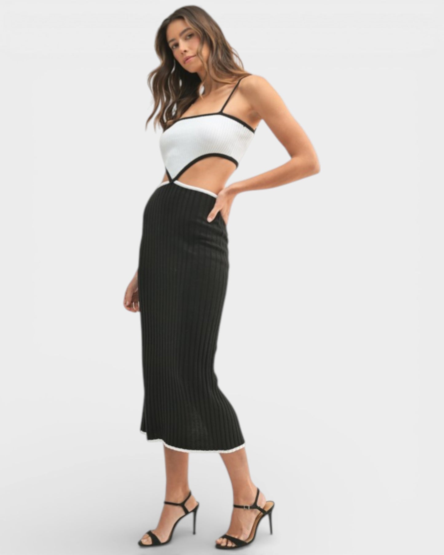 Woman wearing a white top with cut-out design and a black ribbed skirt on a white background