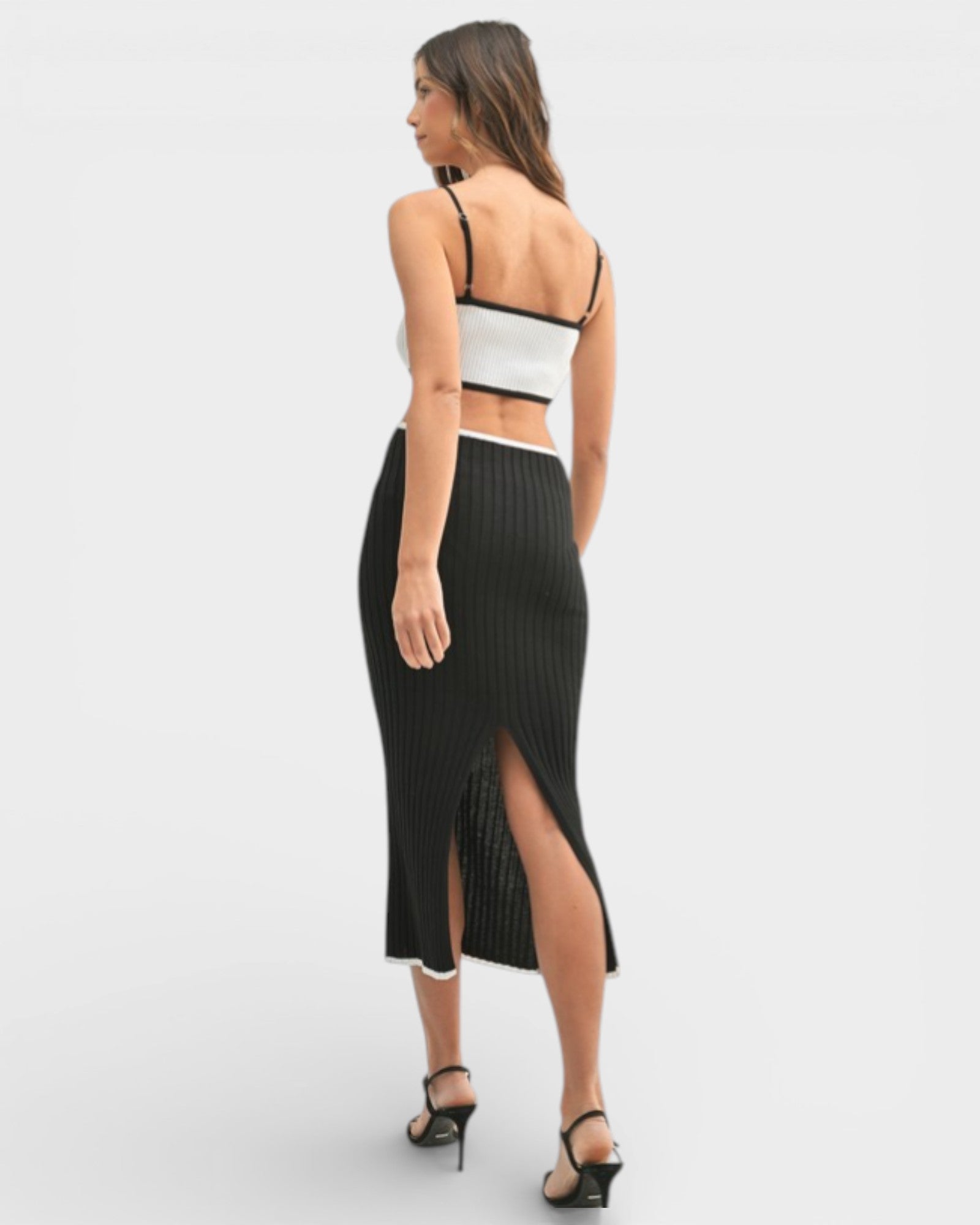 Woman wearing a black ribbed skirt with a high slit on a white background
