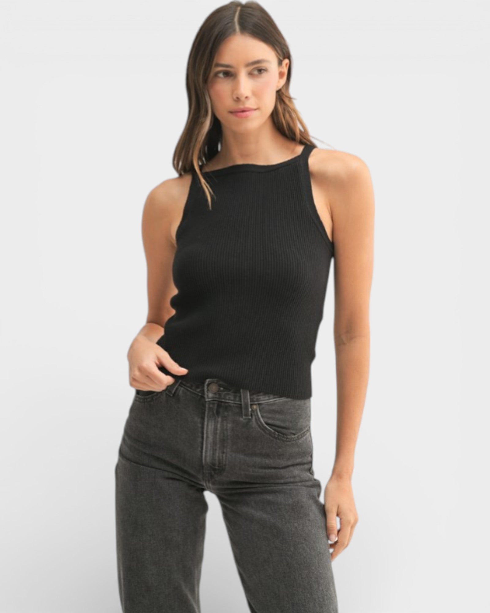 Woman wearing a black tank top and gray jeans on a white background
