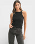 Woman wearing a black tank top and gray jeans on a white background
