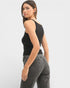 Woman wearing a black sleeveless top and gray jeans on a white background
