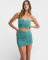 Woman wearing a teal strapless top and skirt set on a white background