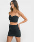 Woman wearing a black strapless top and skirt on a white background