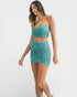 Woman wearing a teal strapless top and skirt set on a white background