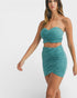 Woman wearing a teal strapless top and skirt set on a white background