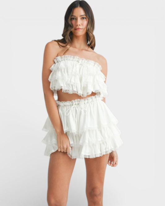 Woman wearing a white ruffled outfit on a plain background