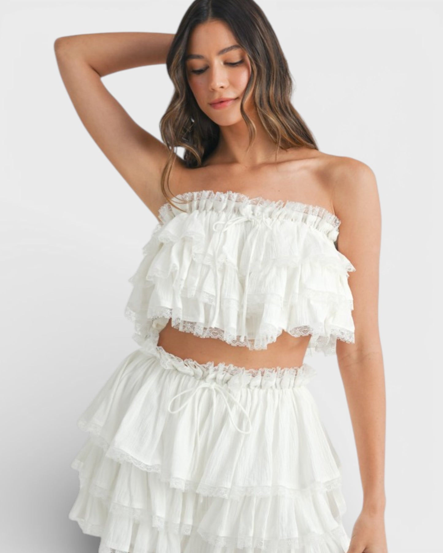 Woman wearing a white ruffled two-piece outfit on a white background