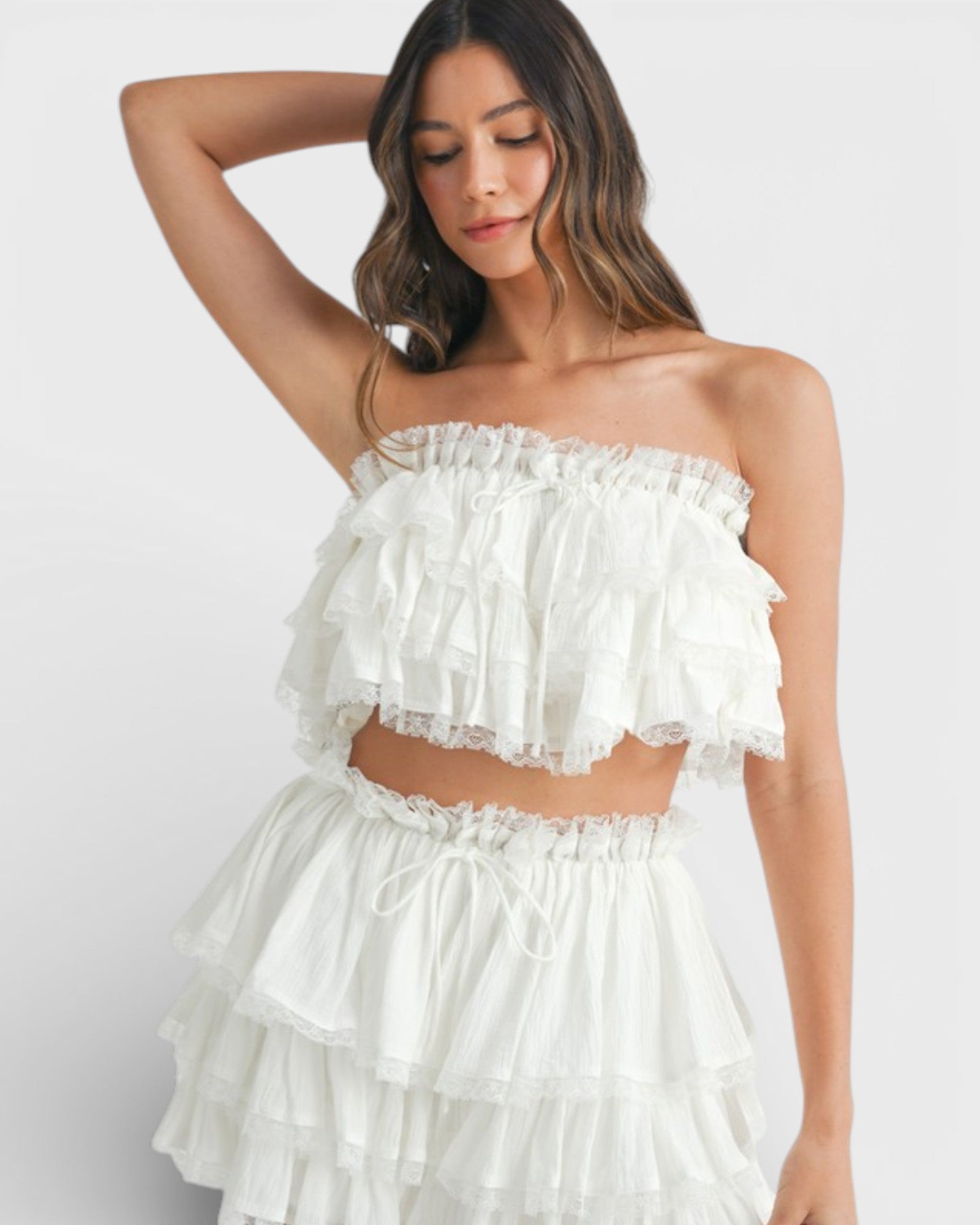 Woman wearing a white ruffled two-piece outfit on a white background