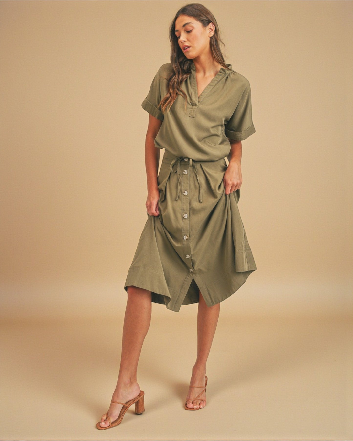 Woman wearing an olive green dress against a beige background