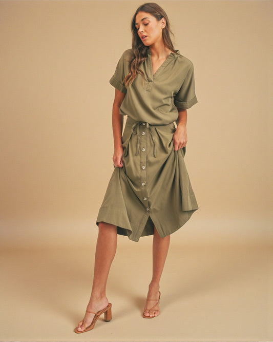 Woman wearing an olive green dress against a beige background