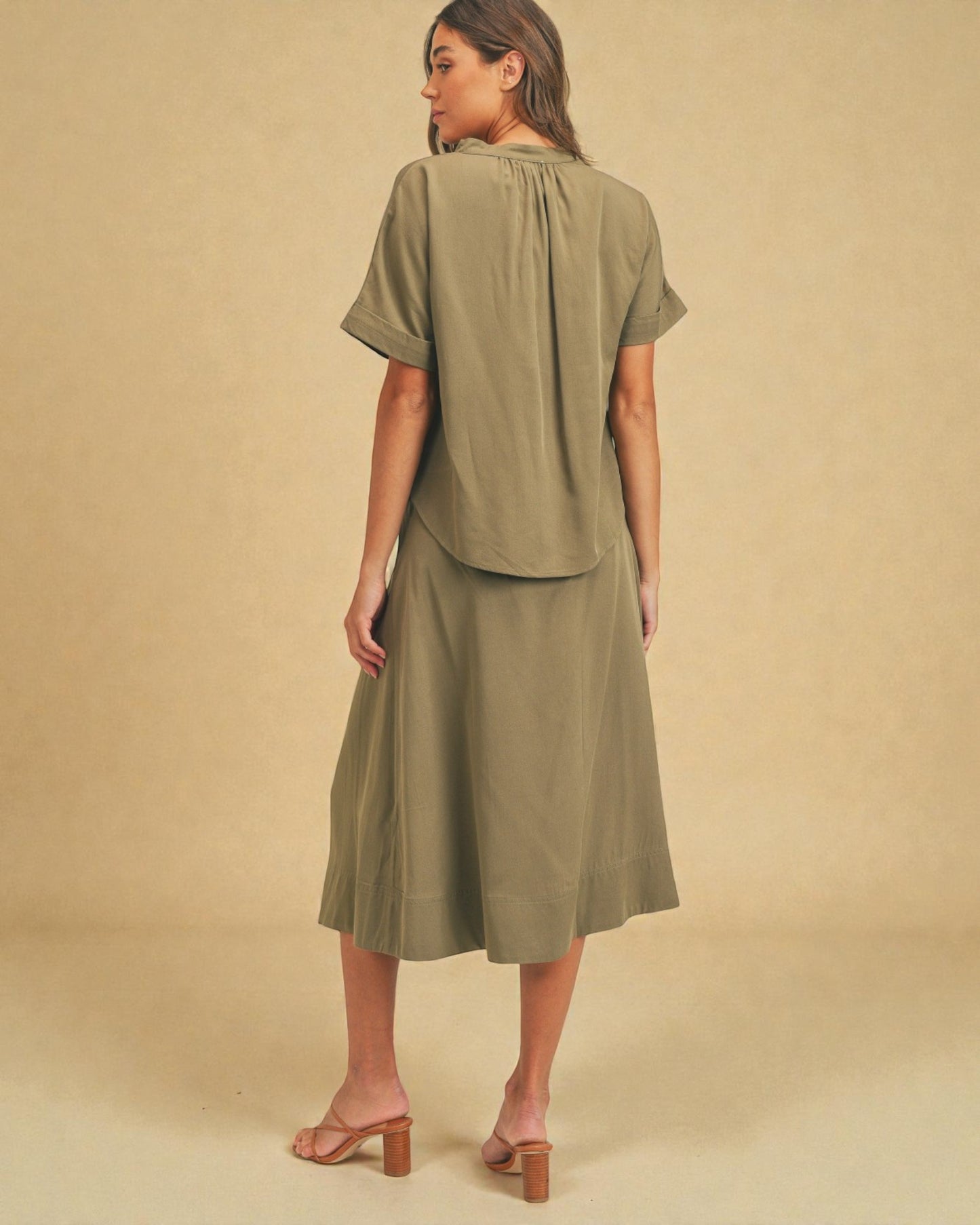 Woman wearing an olive green outfit against a beige background