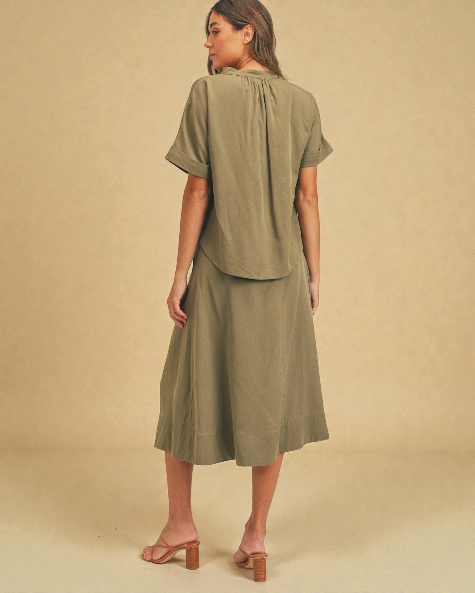 Woman wearing an olive green outfit against a beige background