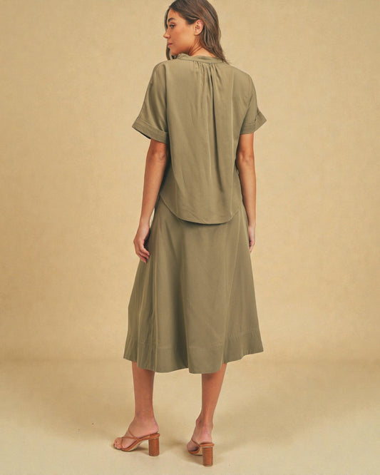 Woman wearing an olive green outfit against a beige background