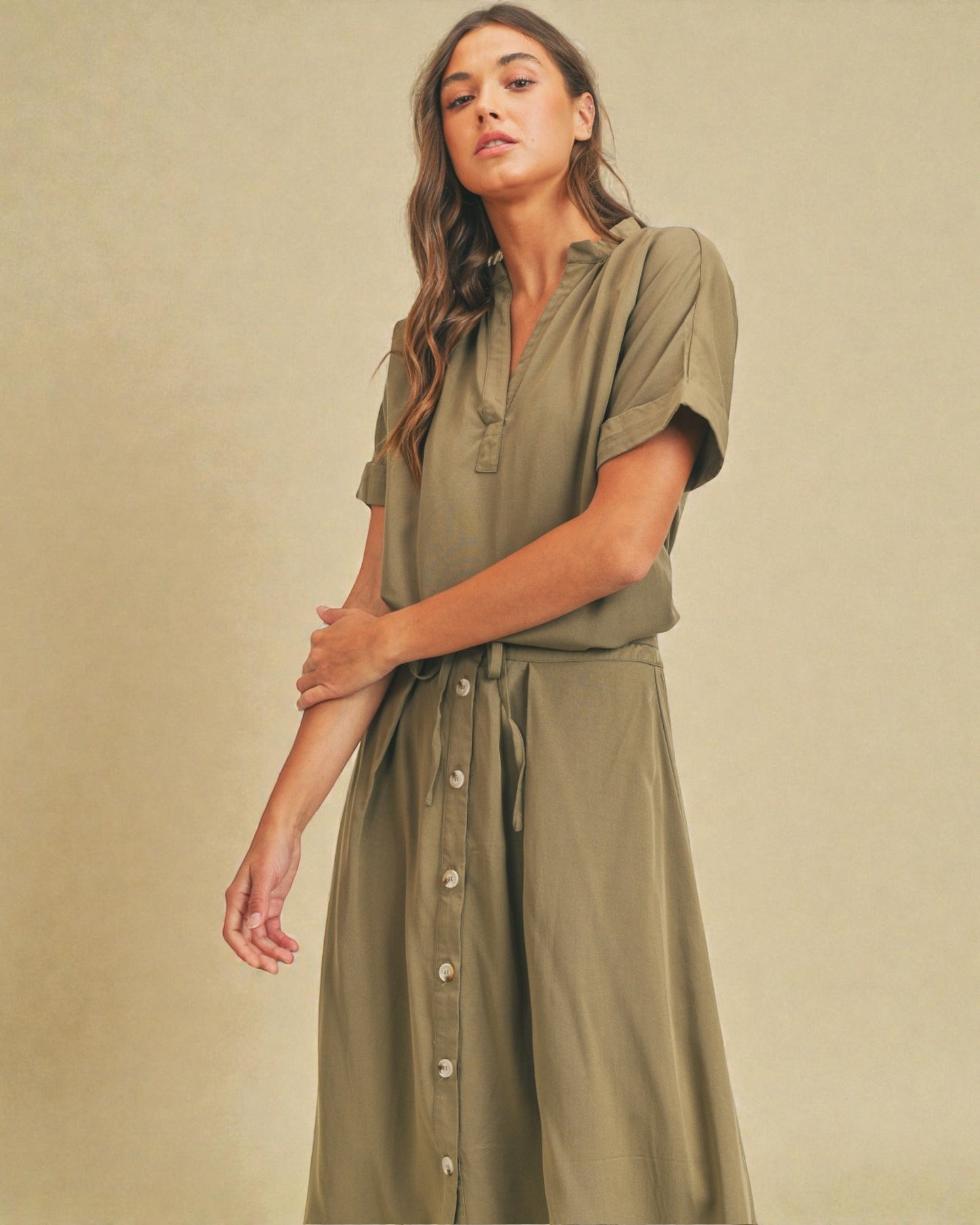 Woman wearing an olive green dress against a beige background