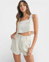 Woman wearing a white sleeveless top and shorts on a white background