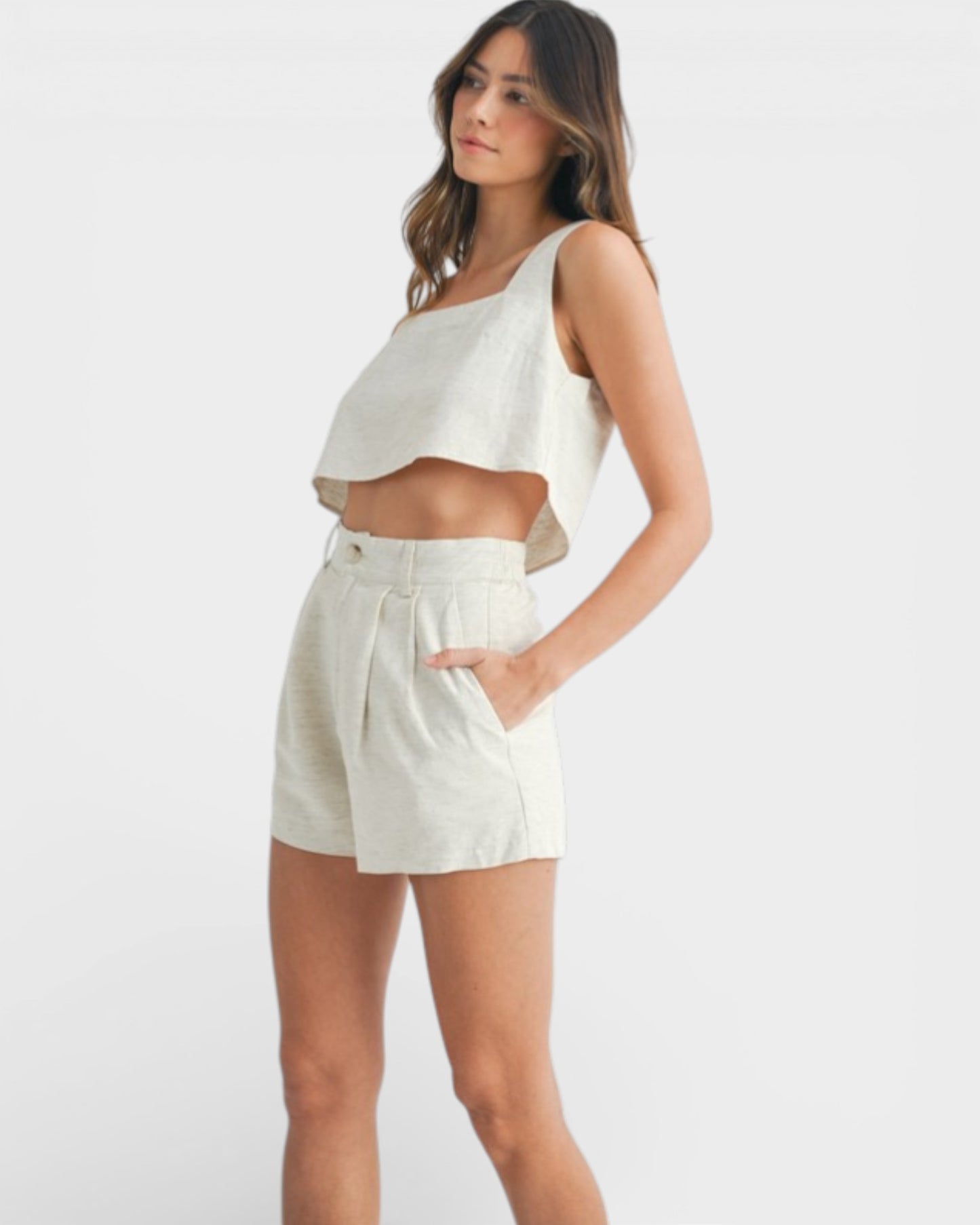 Woman wearing a white sleeveless top and shorts on a white background