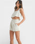 Woman wearing a white sleeveless top and shorts on a white background