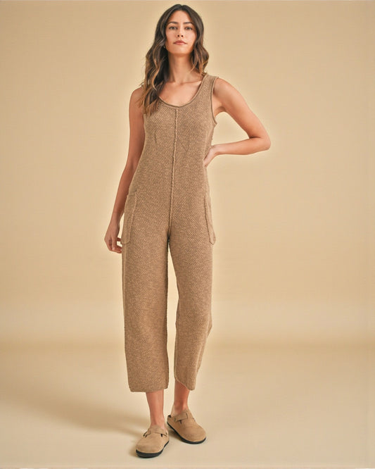 Woman wearing a beige knitted jumpsuit on a beige background