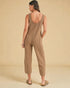 Woman wearing a brown knitted jumpsuit against a beige background