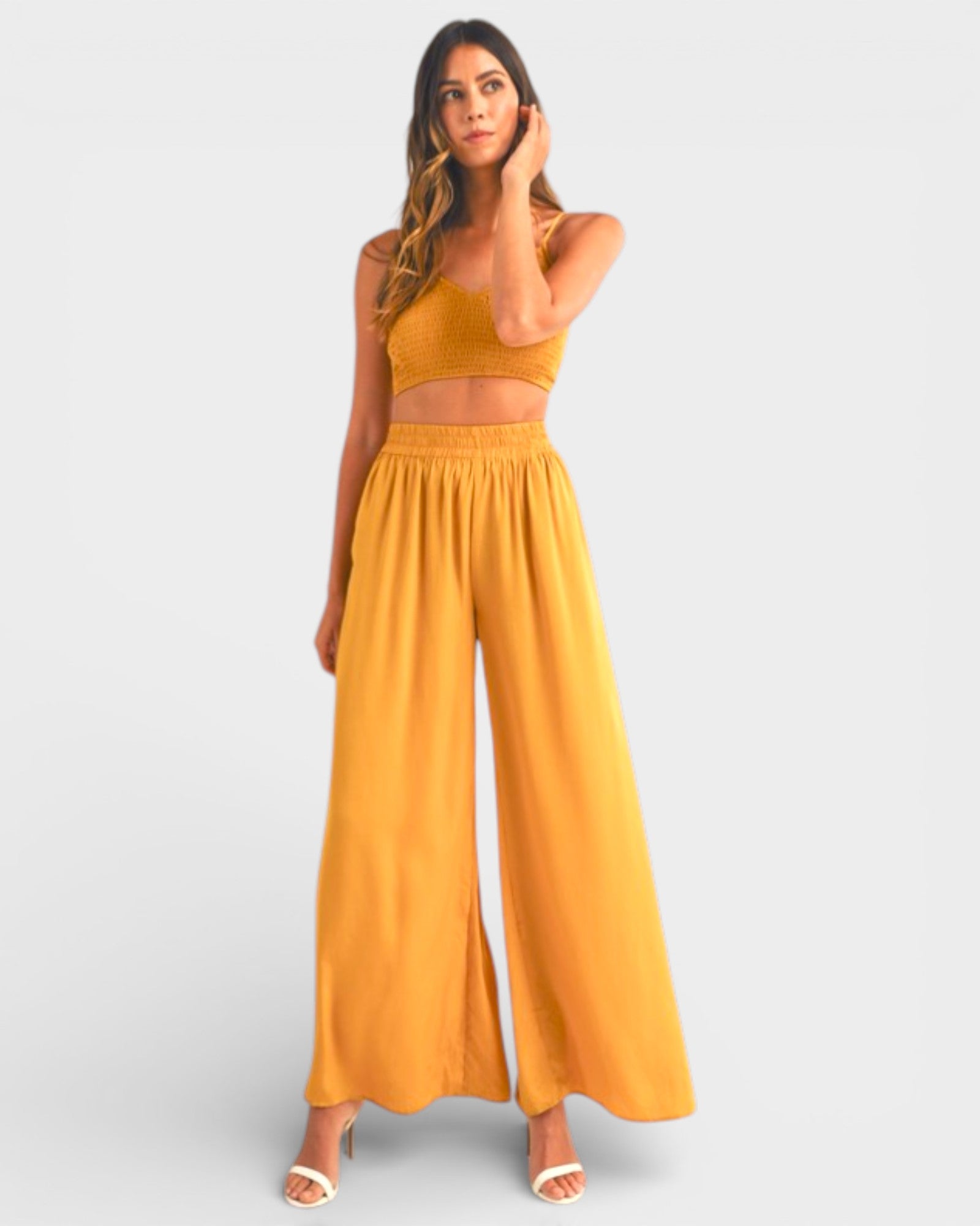 Woman wearing a mustard yellow outfit on a light gray background