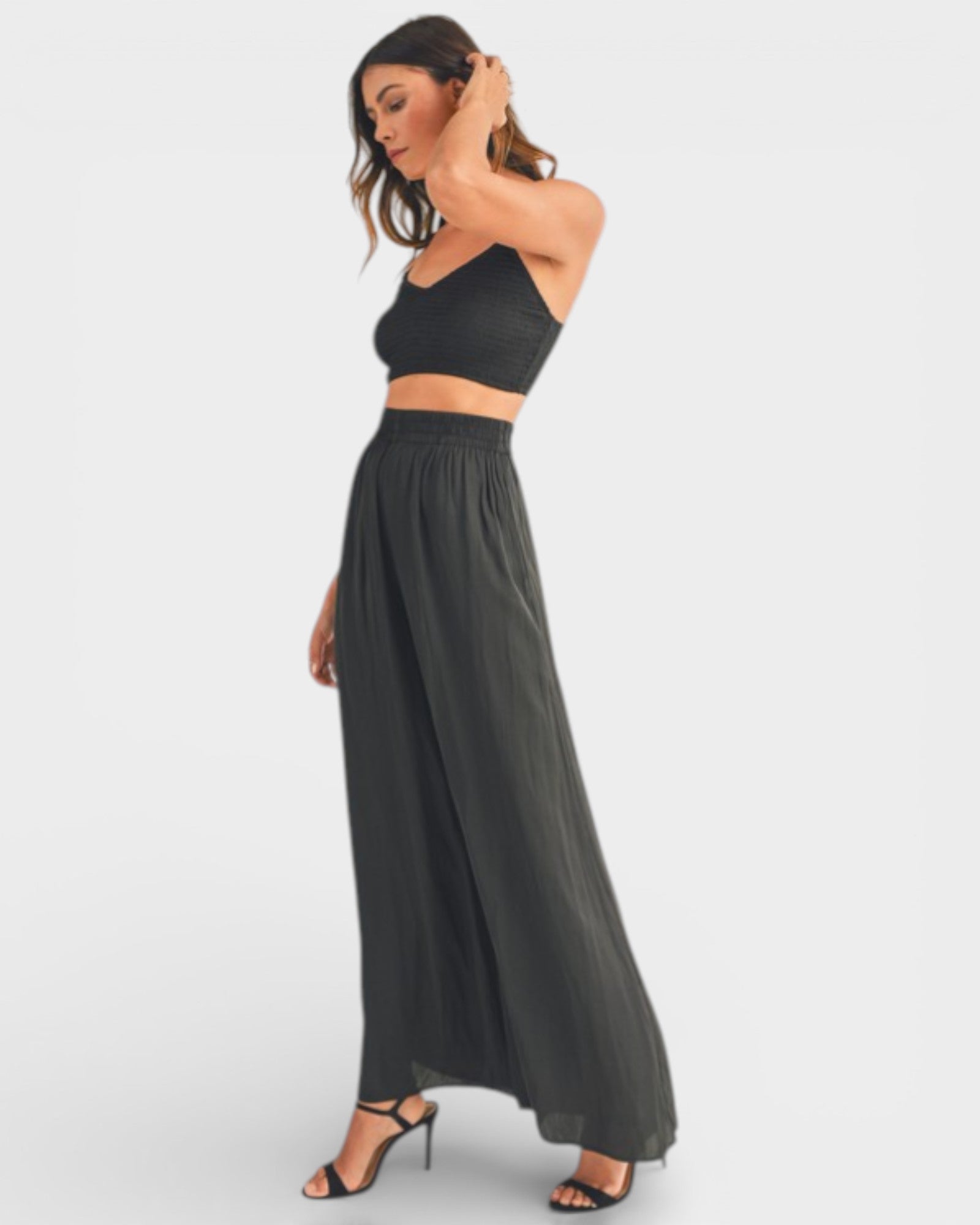 Woman wearing a black strap top and long black skirt on a white background