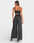 Woman wearing a black strappy top and wide-leg pants on a white background