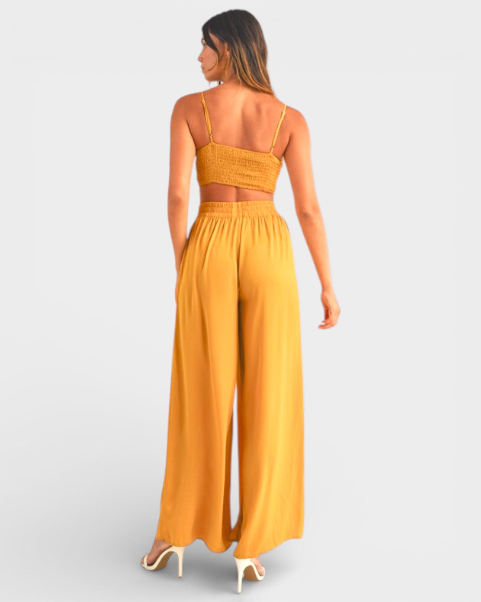 Woman wearing a mustard yellow jumpsuit on a light gray background