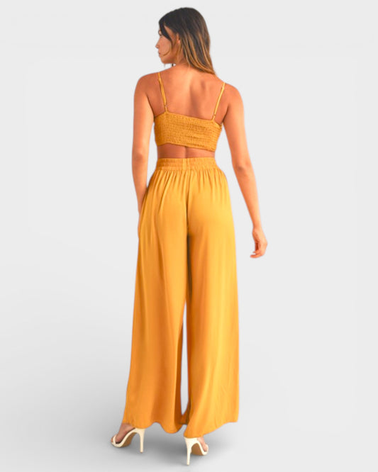 Woman wearing a mustard yellow jumpsuit on a light gray background