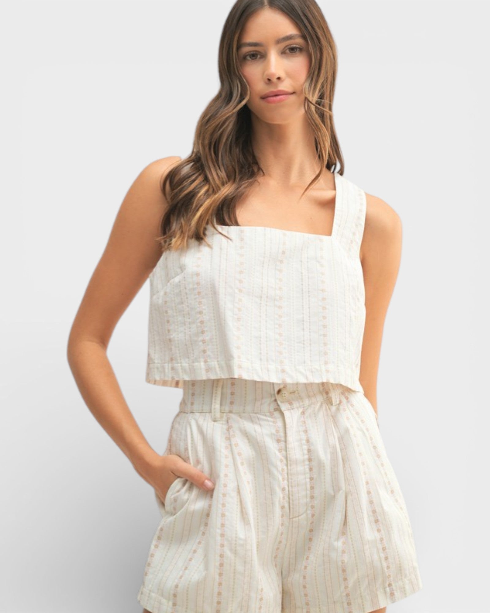 Woman wearing a white sleeveless top and matching shorts on a light gray background