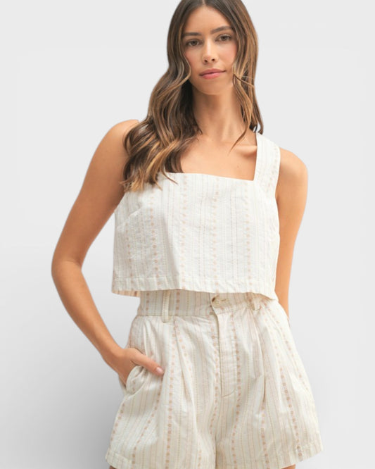 Woman wearing a white sleeveless top and matching shorts on a light gray background