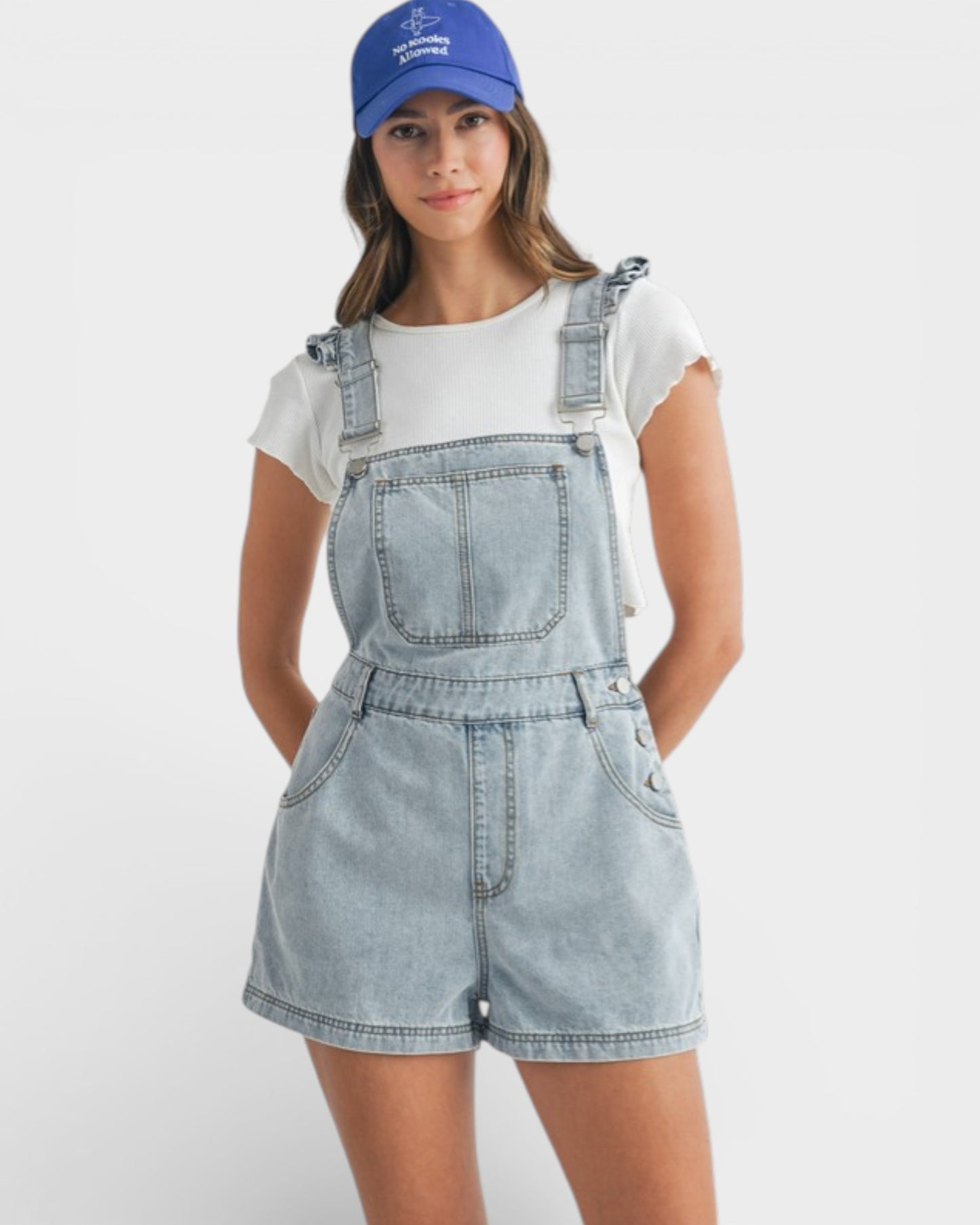 Person wearing denim overalls and a blue cap on a white background