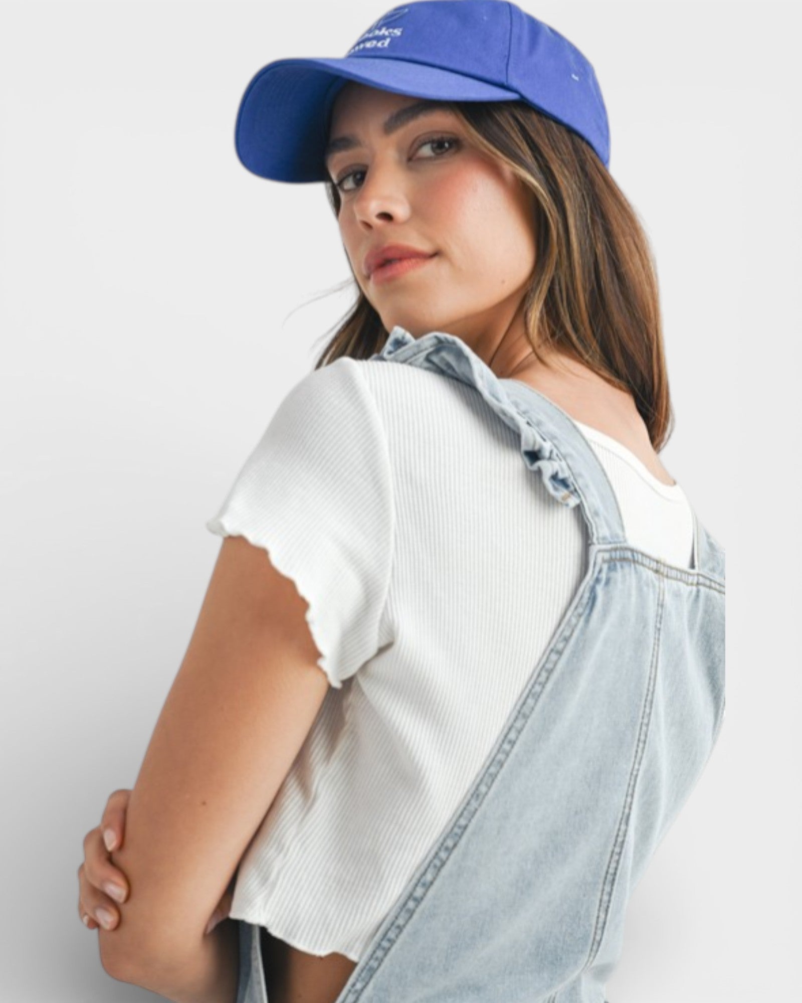 Woman wearing a blue cap and denim overalls on a white background
