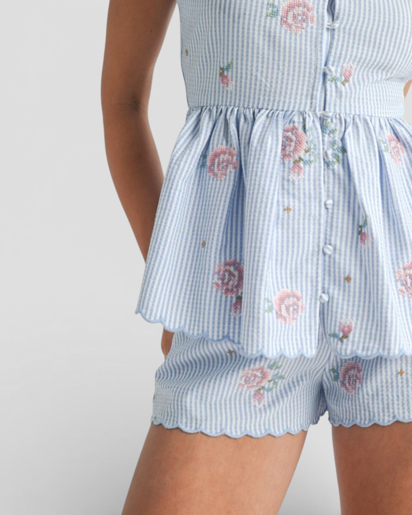 Light blue checkered romper with floral patterns on a plain background