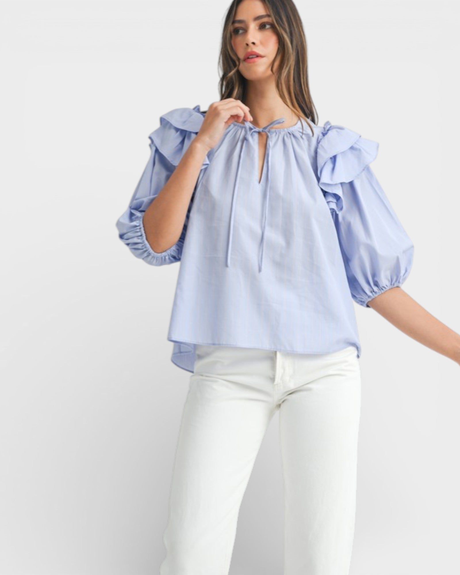 Woman wearing a light blue blouse with ruffled sleeves on a white background