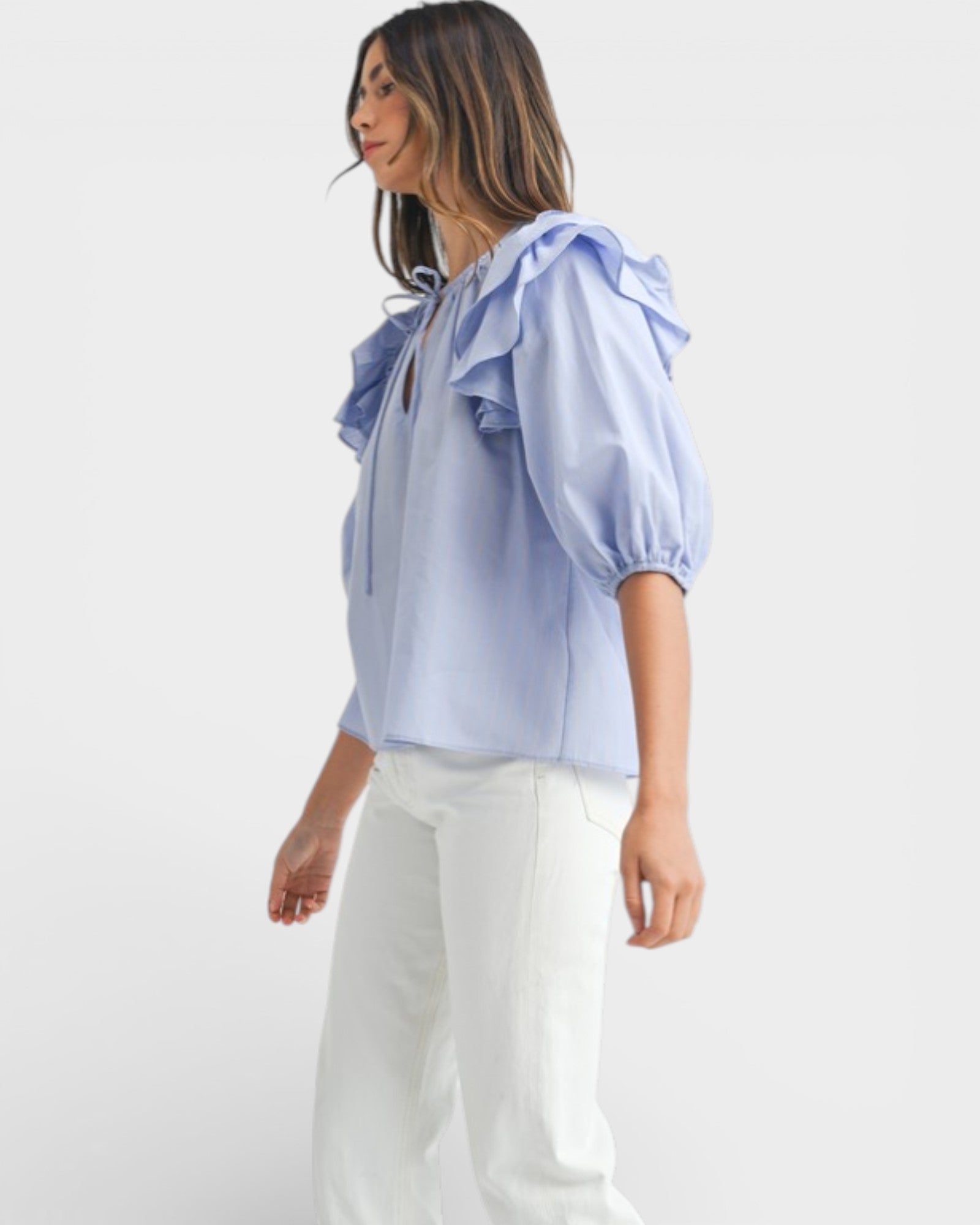 Woman wearing a light blue blouse with ruffled details on a white background
