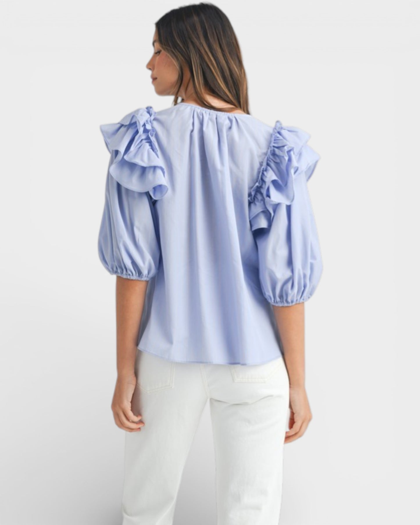 Woman wearing a light blue blouse with ruffled sleeves on a white background
