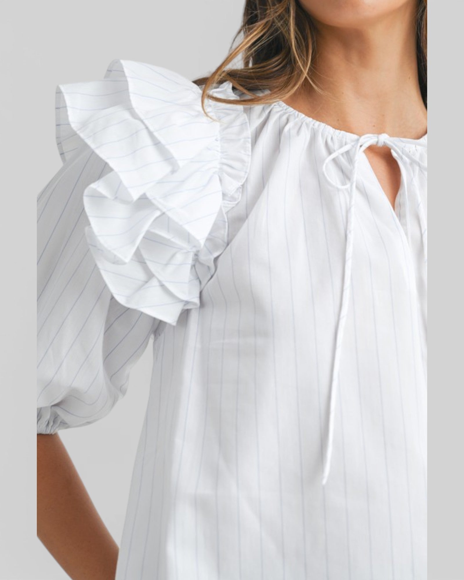 White blouse with ruffled sleeves on a plain background