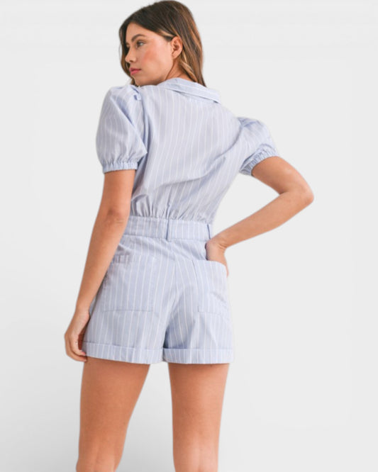 Woman wearing a blue and white striped romper on a plain background